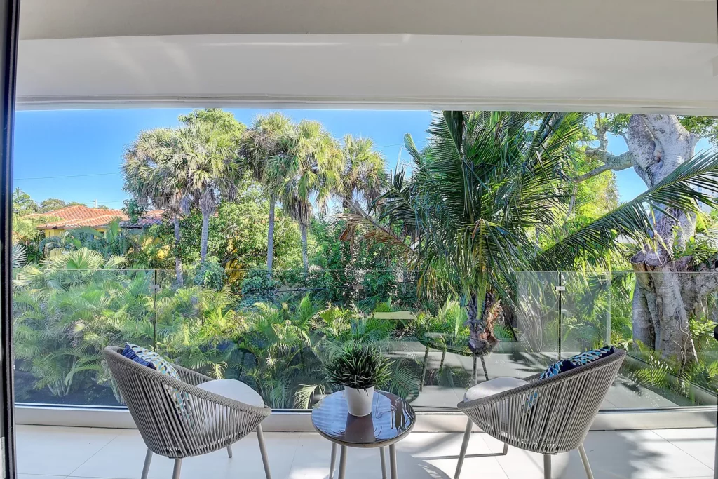 Modern room with large windows offering a view of a lush garden with palm trees.