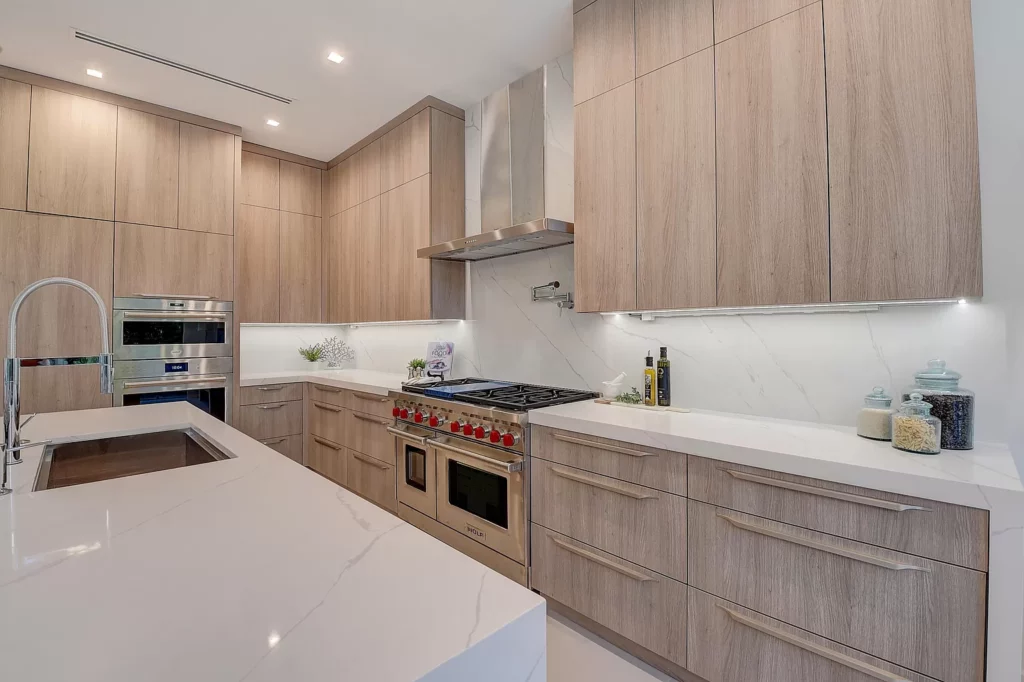 Modern kitchen interior with wooden cabinets, white countertops, and built-in appliances.