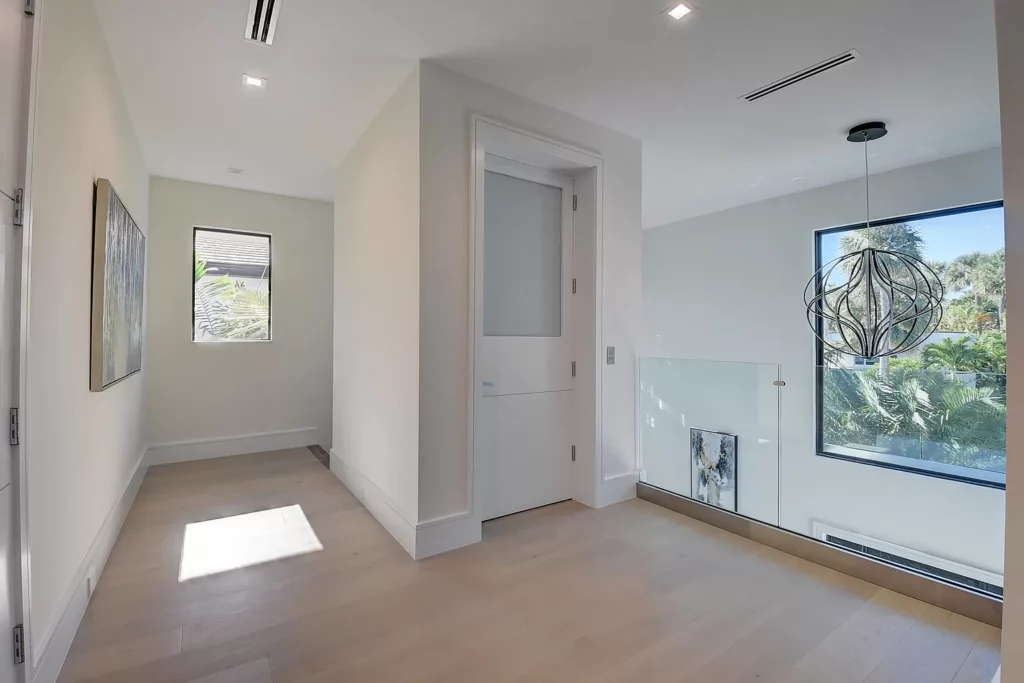 Bright and modern hallway with artistic light fixture and large windows.