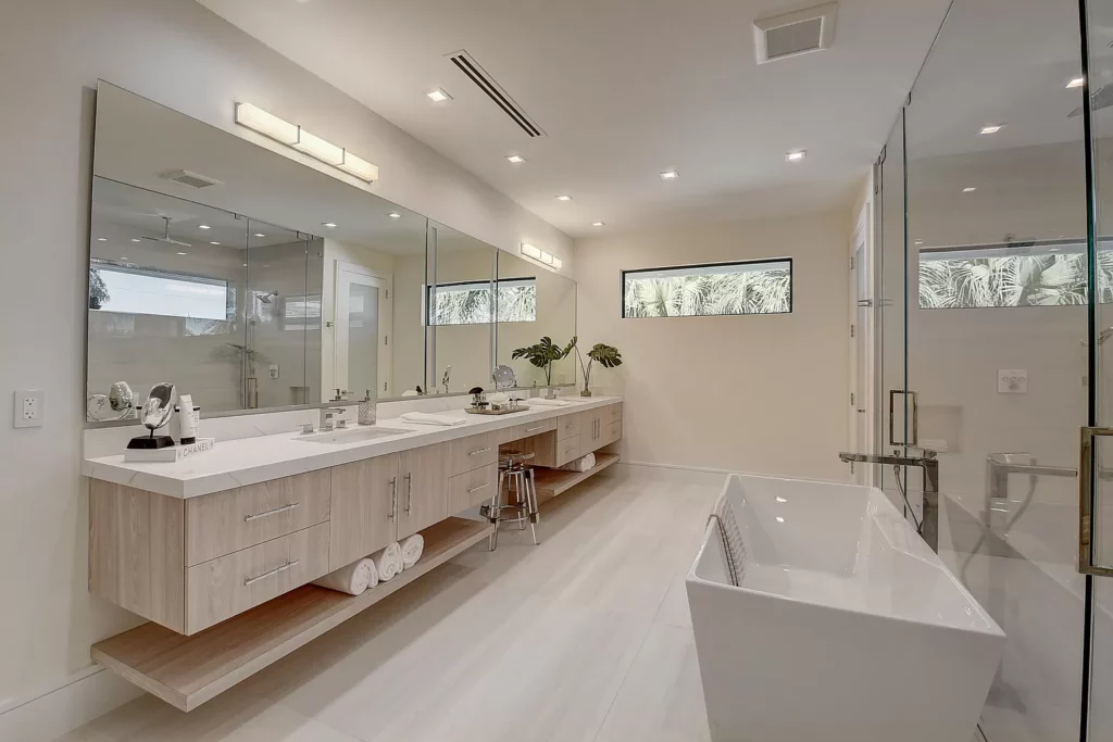 Modern bathroom interior with a freestanding tub, dual vanity, and large mirrors.