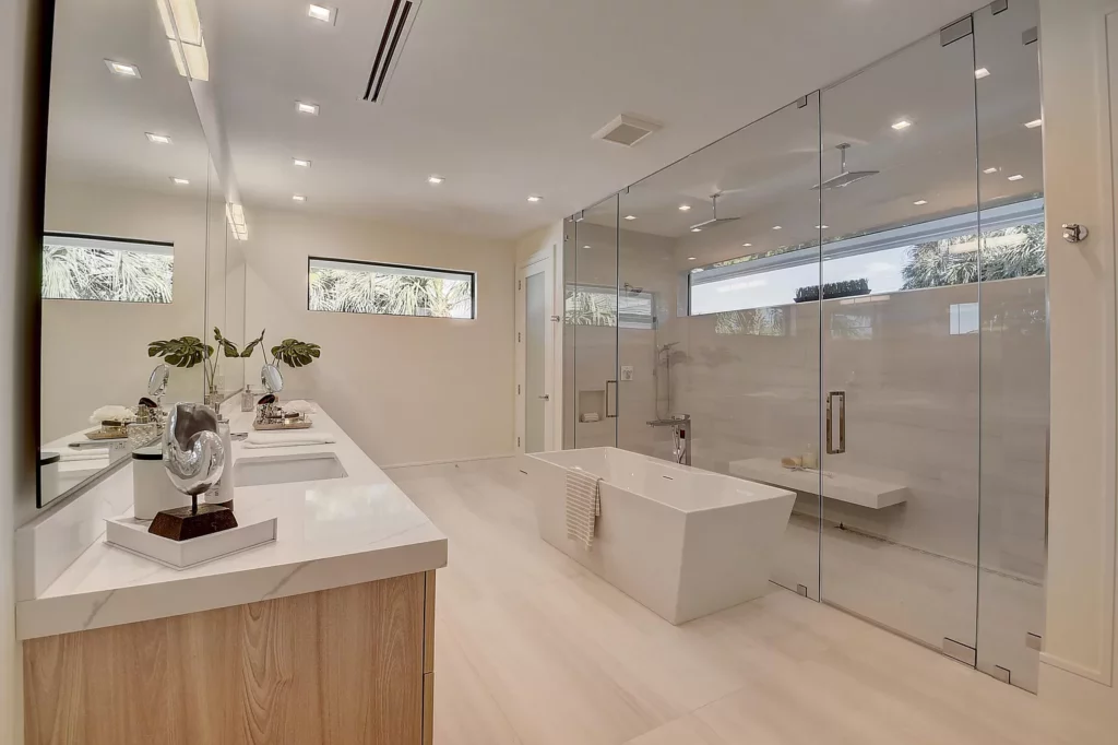 Modern bathroom with a freestanding bathtub, dual vanity, and glass-enclosed shower area.