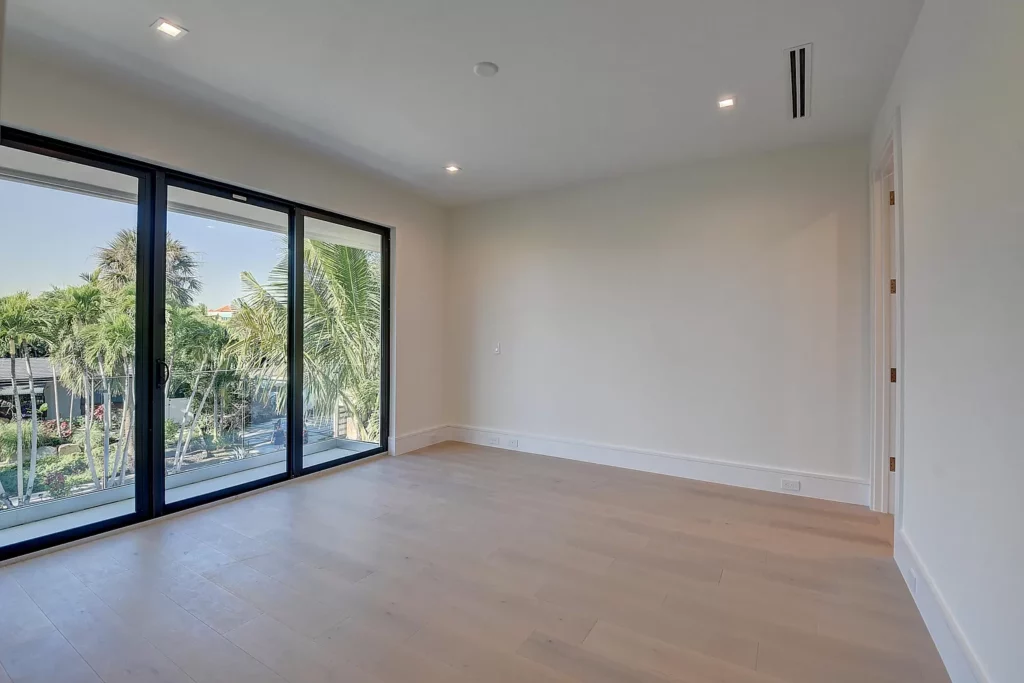 Empty room with large sliding glass doors and a view of outdoor greenery.