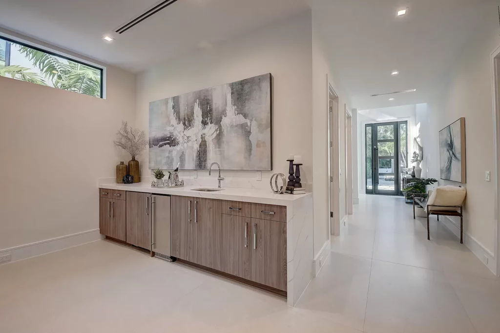 Modern kitchen interior with wooden cabinetry, marble countertop, and abstract wall art.