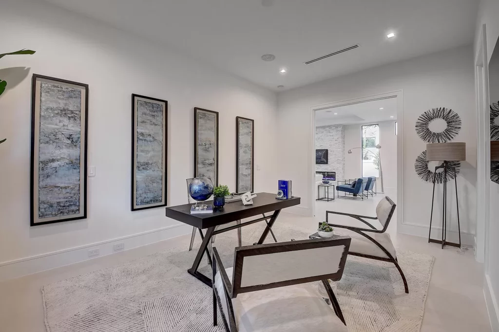 A modern, minimalist styled room with a wooden table, two chairs, decorative art pieces on the wall, and a stylish floor lamp.