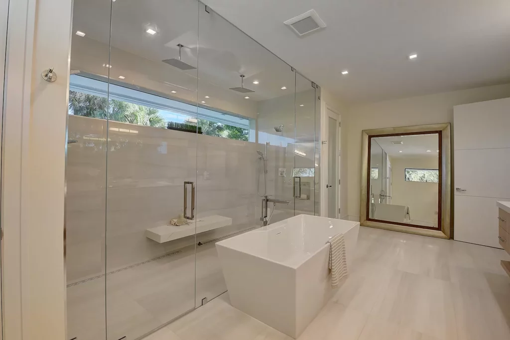 Modern bathroom with glass shower enclosure, freestanding tub, and minimalist design.