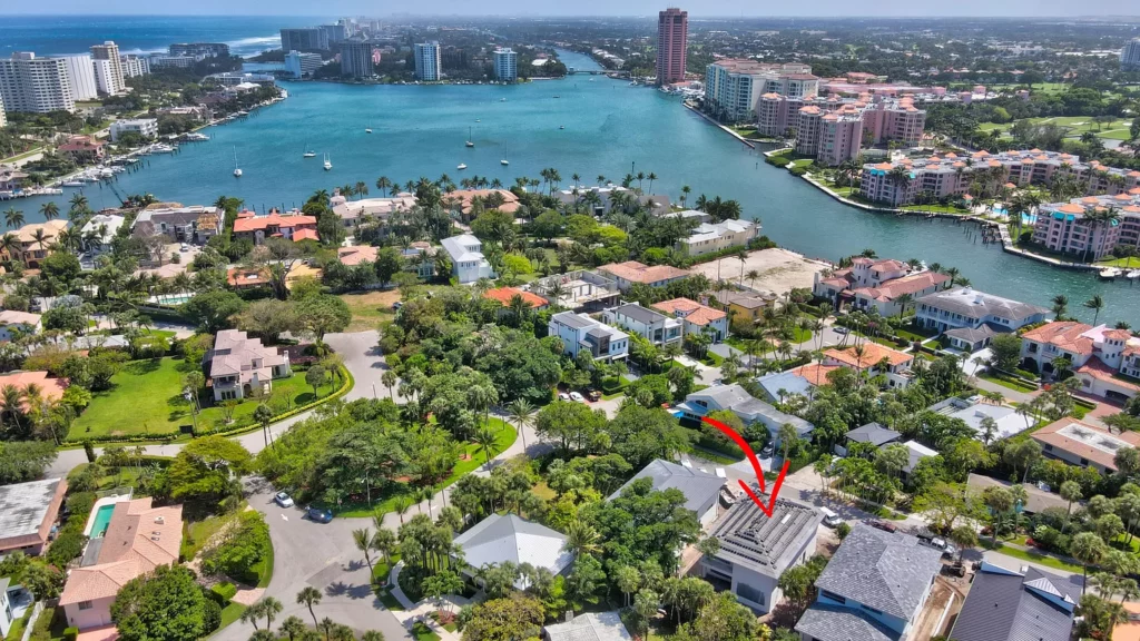 Aerial view of a coastal residential area with a red arrow pointing to a specific property.