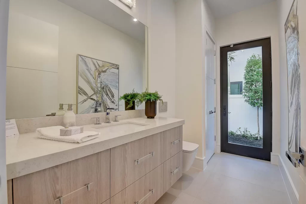Modern bathroom with double sink vanity and entrance to a courtyard.